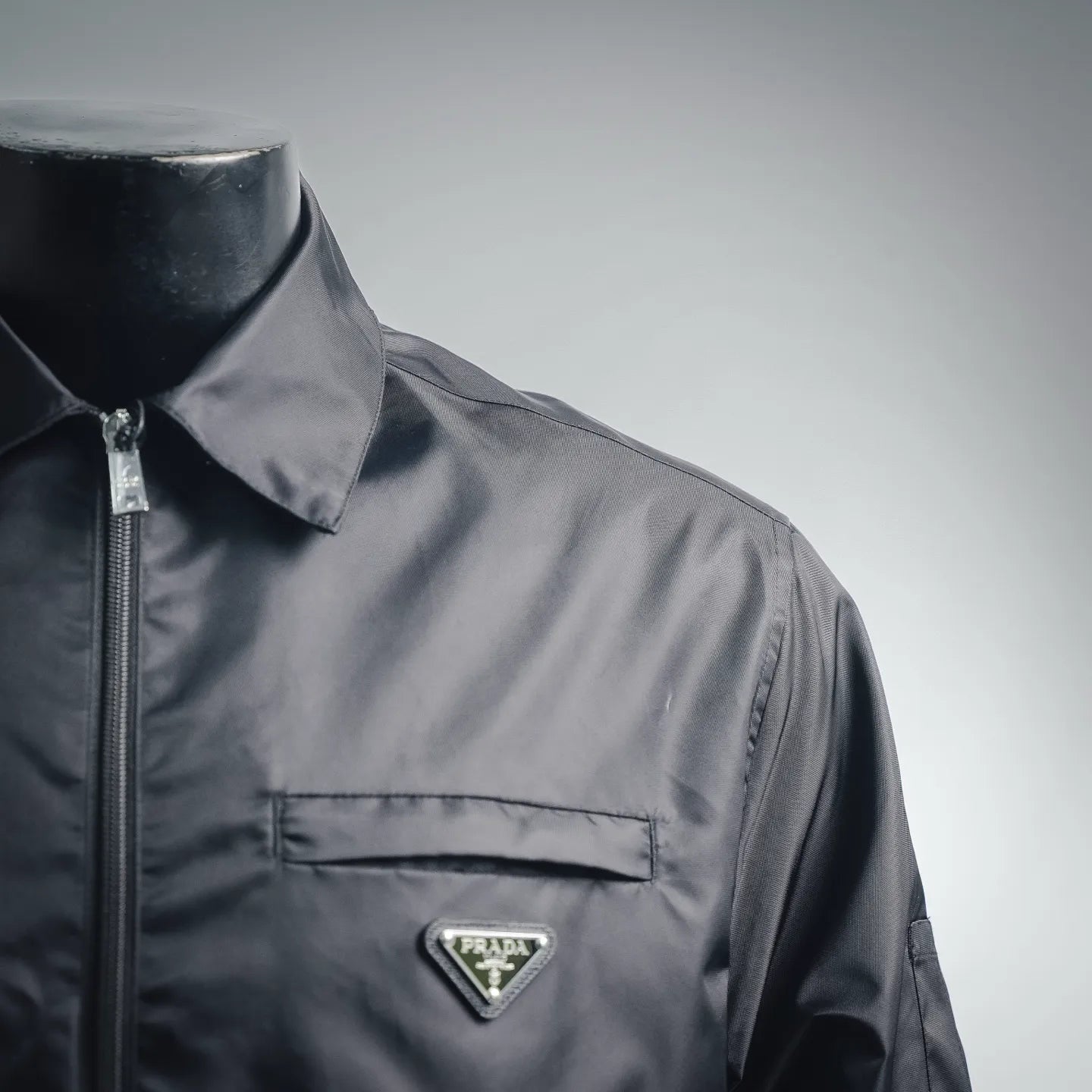 Prada dark gray jacket front shoulder and chest with triangular logo badge