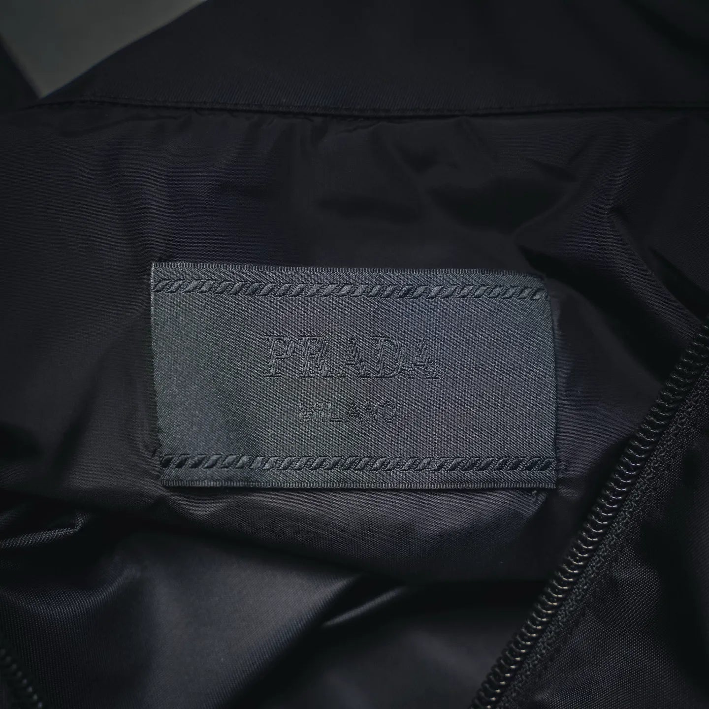 Prada Milano interior label on dark gray jacket with visible zipper track