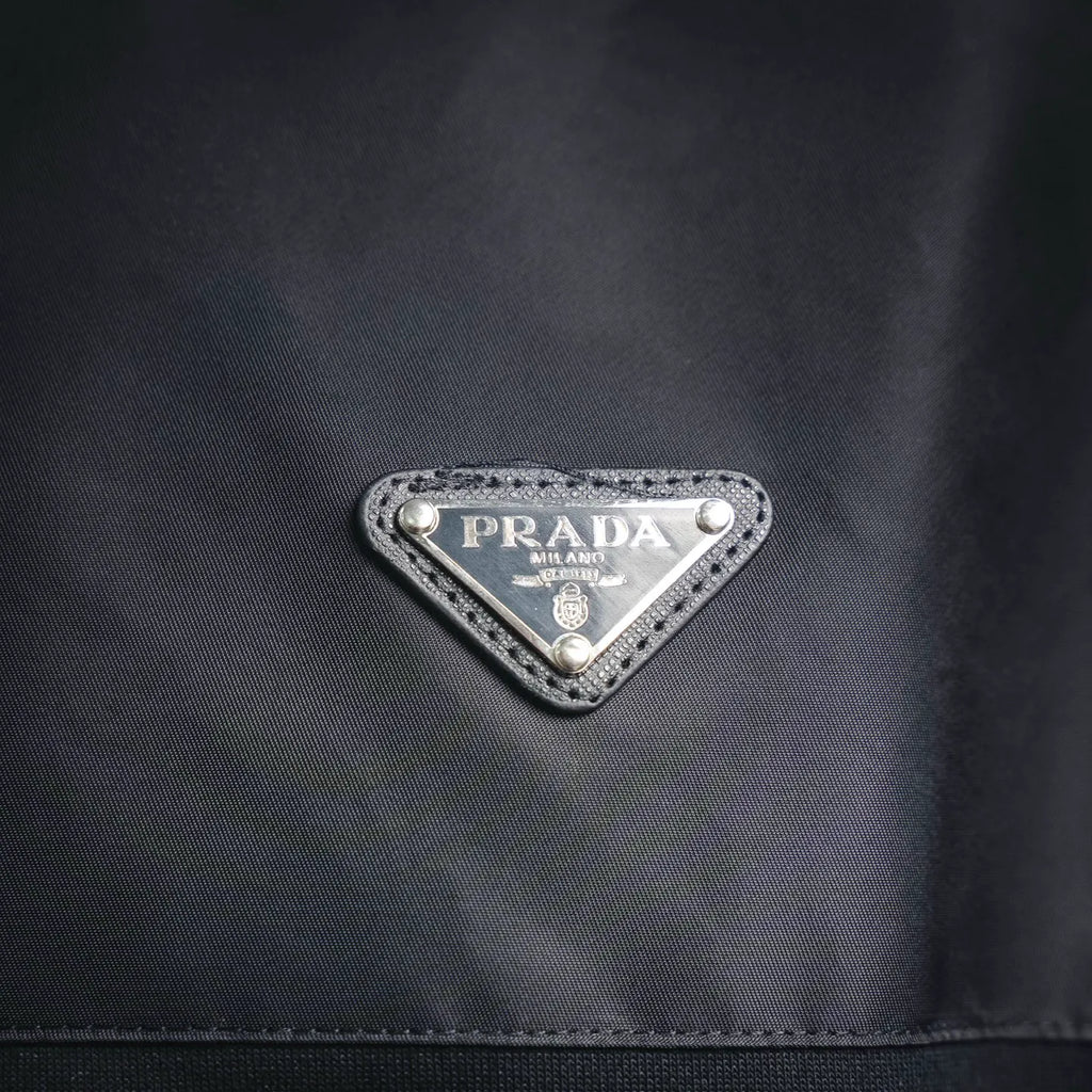Prada triangular logo badge on dark jacket chest