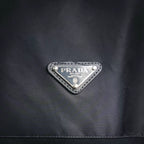 Prada triangular logo badge on dark jacket chest