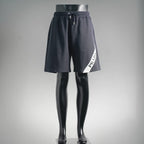 Dark drawstring shorts with side patch logo, elastic waist and tapered legs