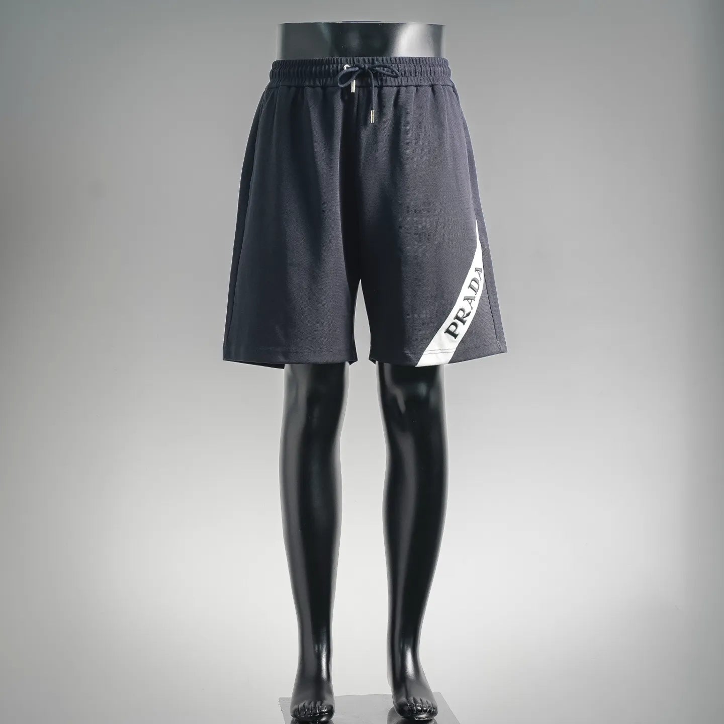 Dark drawstring shorts with side patch logo, elastic waist and tapered legs