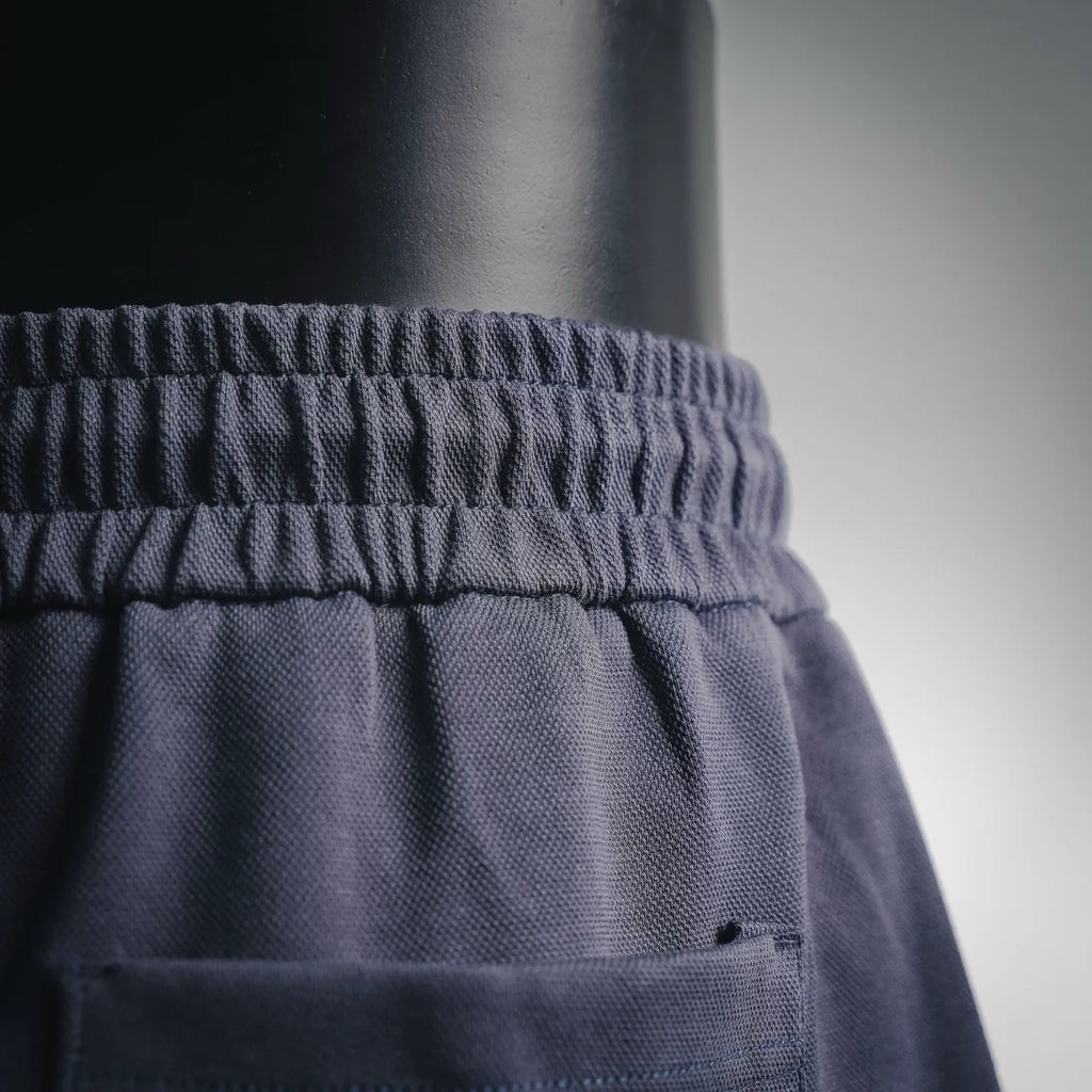 Dark shorts waistband area with small Prada logo patch on front pocket