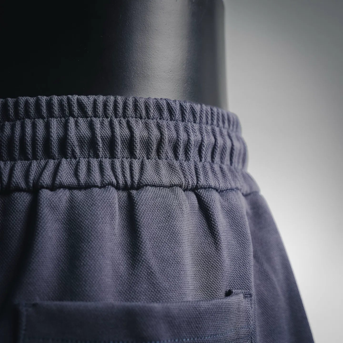 Dark shorts waistband area with small Prada logo patch on front pocket
