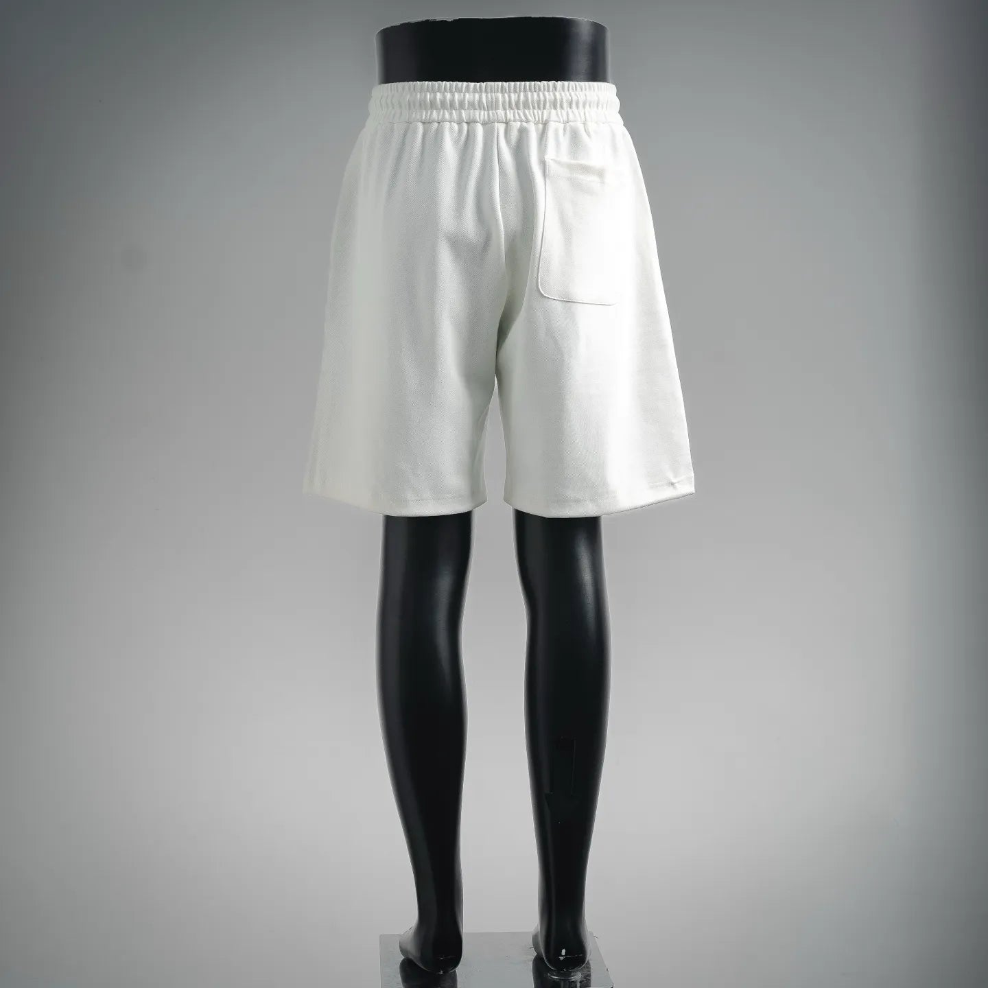 White drawstring shorts with elastic waistband, front view from behind
