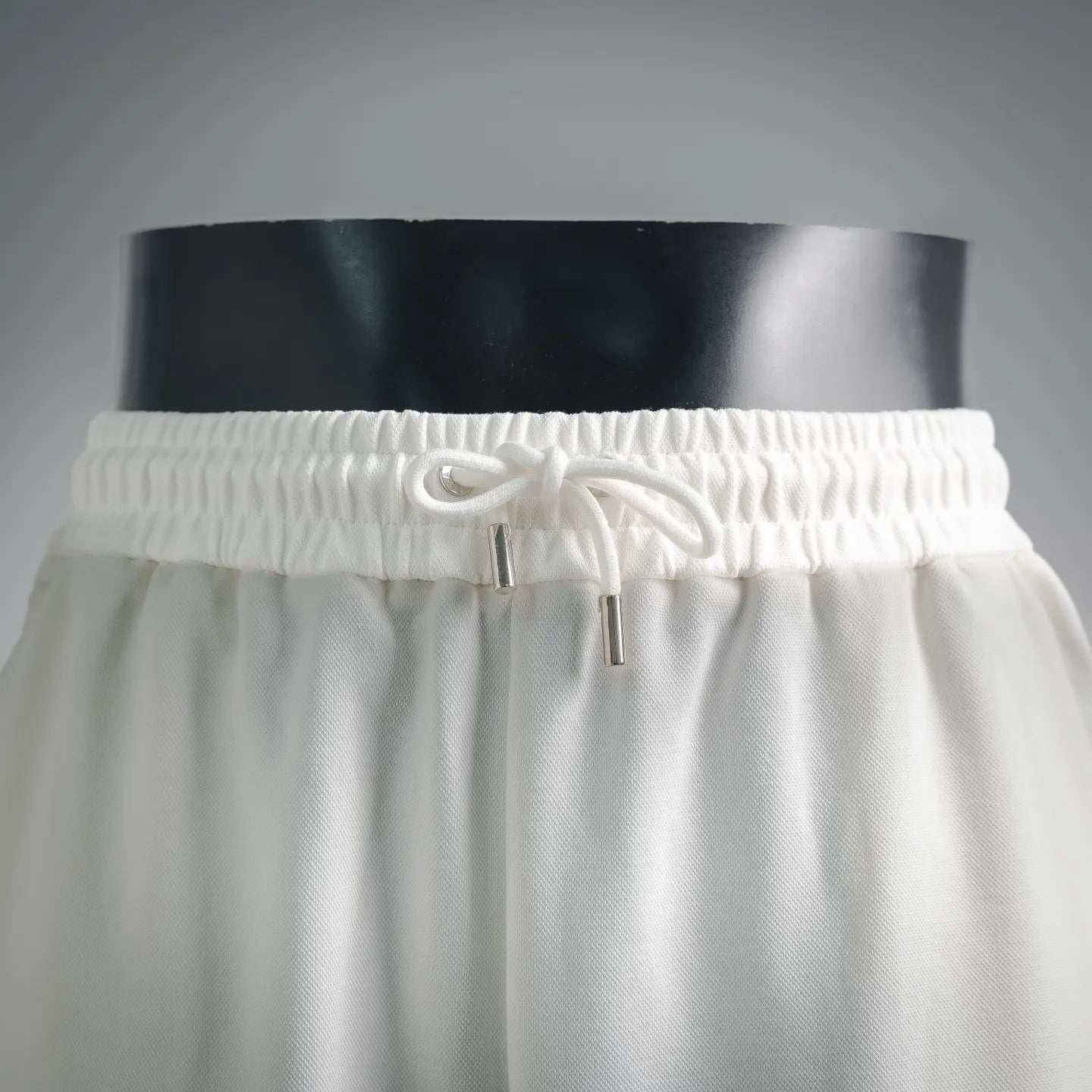 White drawstring shorts with elastic waistband and metal eyelets