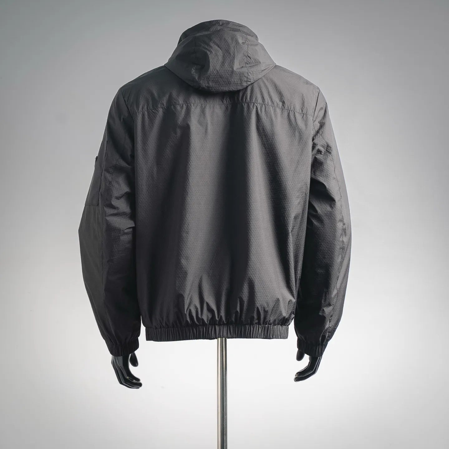 Black hooded jacket, back view with gathered hem and elastic cuffs
