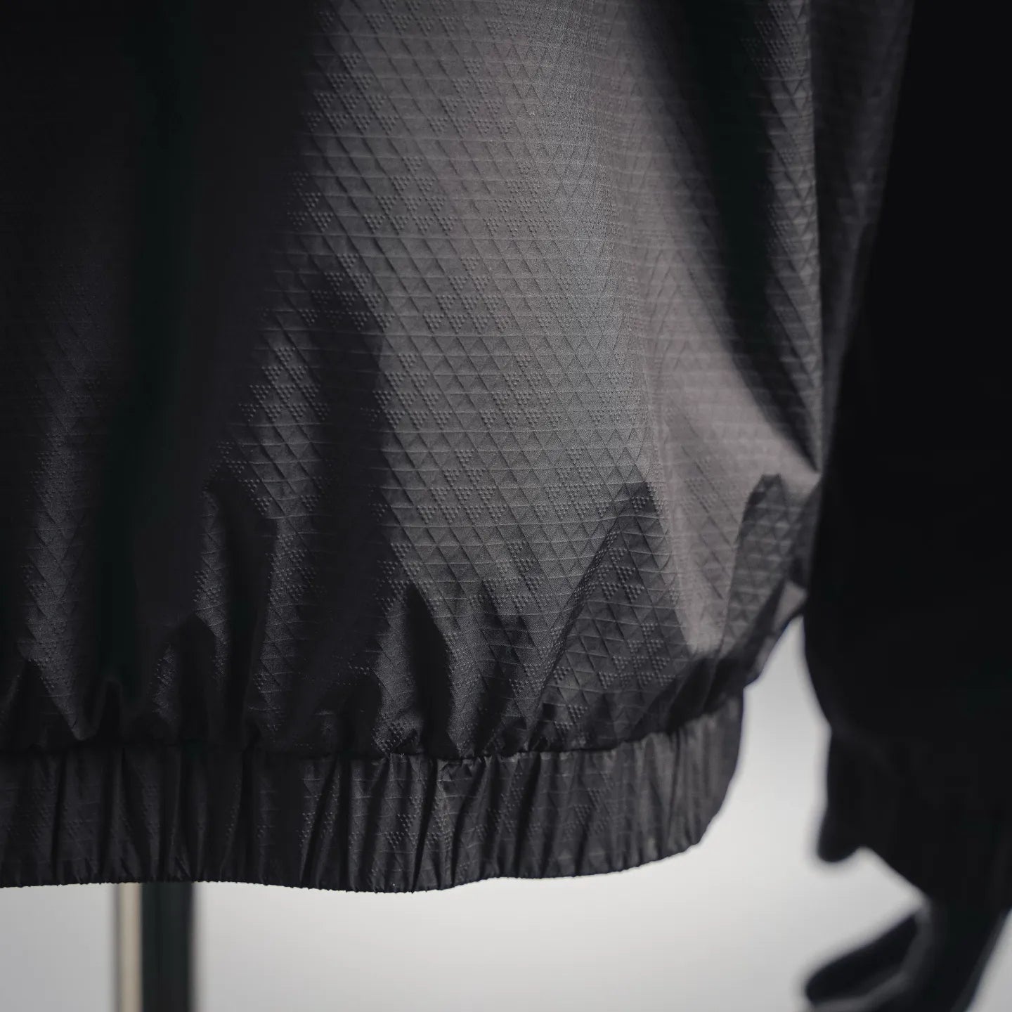 Black jacket hem with elastic band and textured diamond fabric pattern