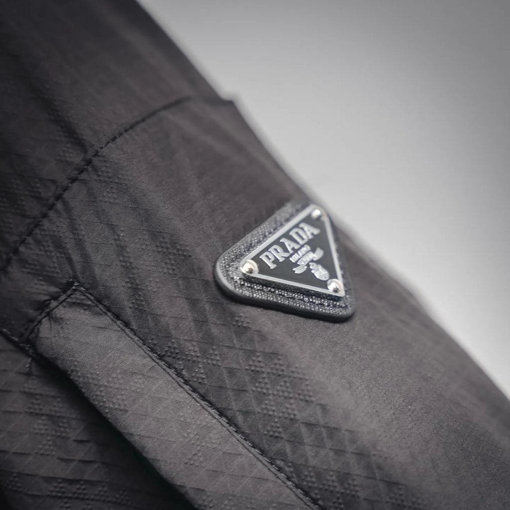 Prada logo patch on black jacket near zipper and shoulder seam