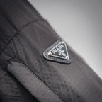 Prada logo patch on black jacket near zipper and shoulder seam