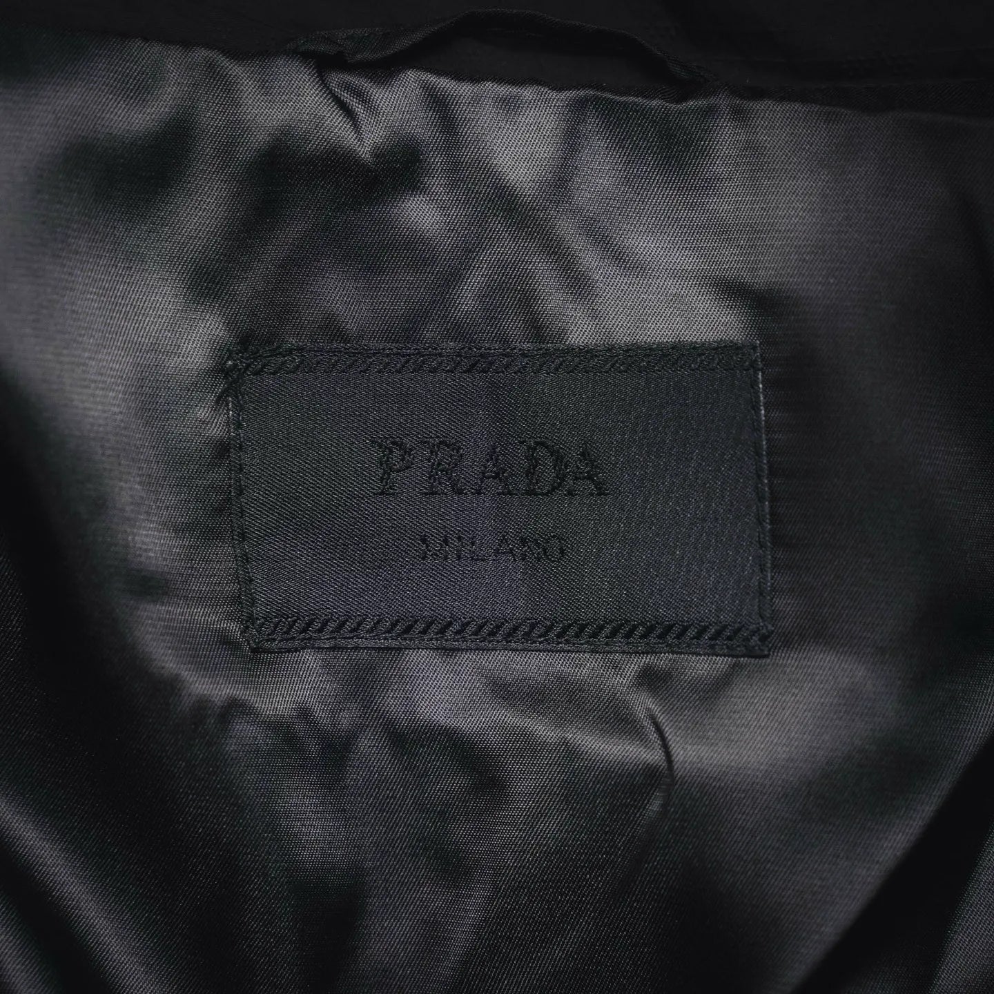 Black fabric care label showing PRADA printed text