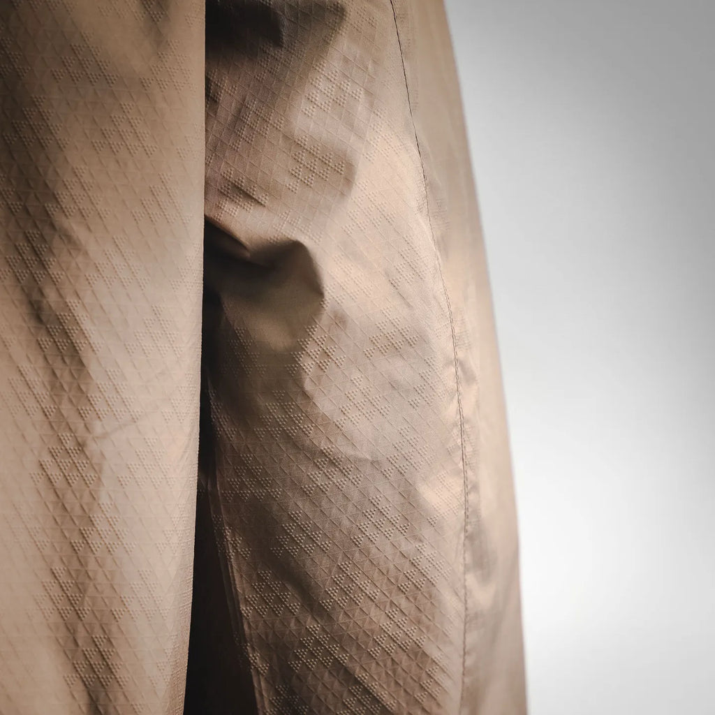 Tan jacket fabric close-up with subtle quilted grid texture