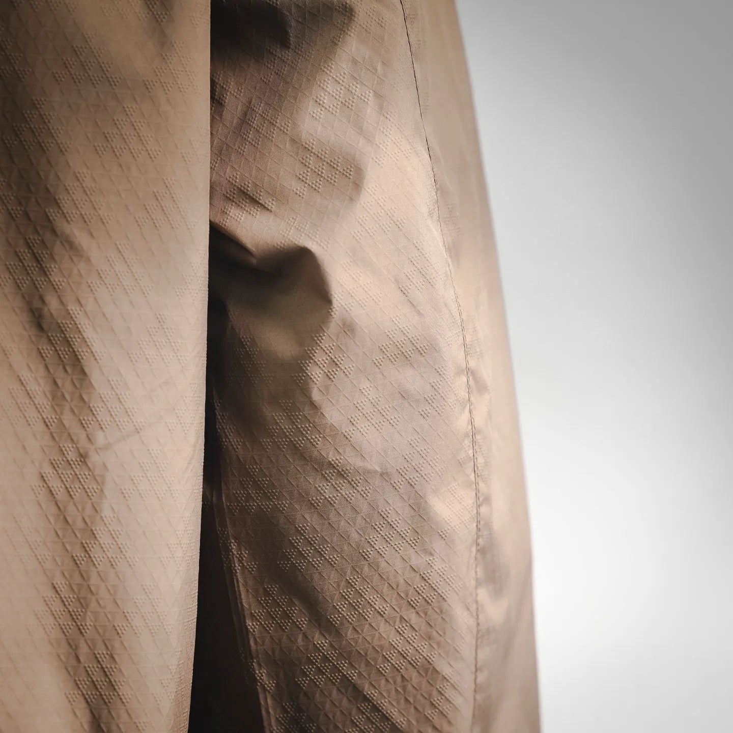 Tan jacket fabric close-up with subtle quilted grid texture