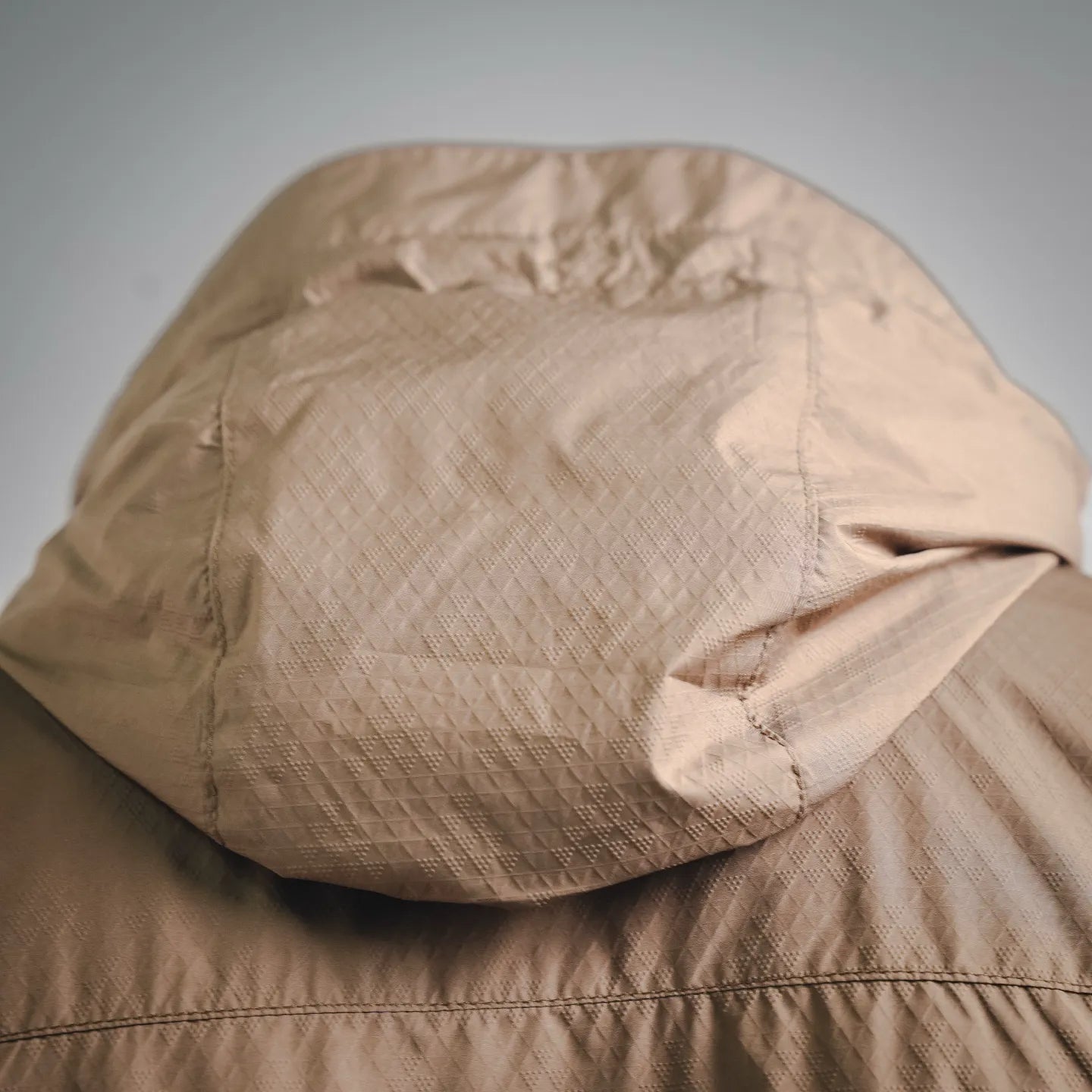 Tan hooded jacket close-up with quilted textured fabric