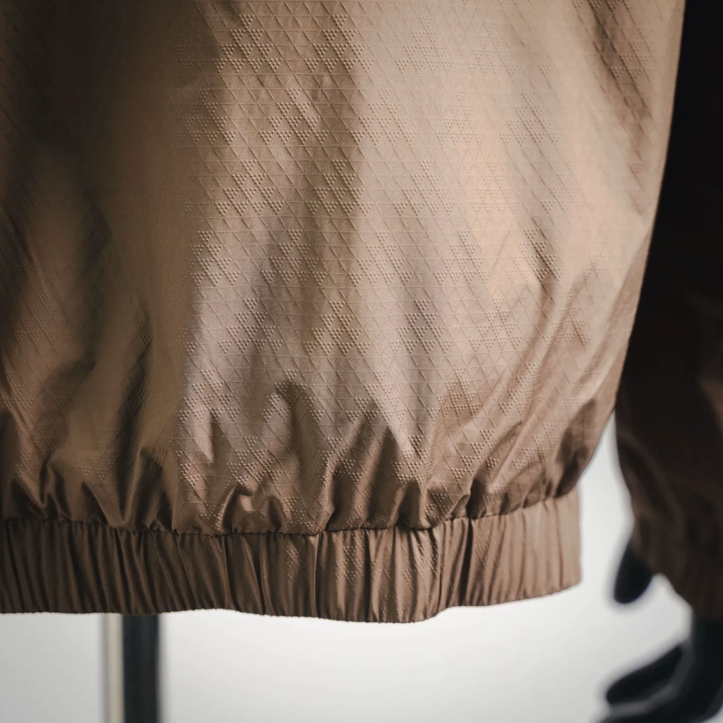 Tan jacket with elastic waistband detail and quilted fabric finish