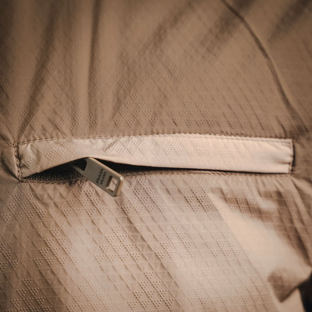 Tan Prada jacket close-up of inner seam and woven logo tag