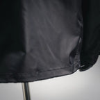 Black jacket bottom hem close-up with stitched seam and slight fabric gathering