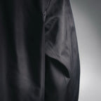 Black jacket side panel close-up with stitched seam and pocket opening