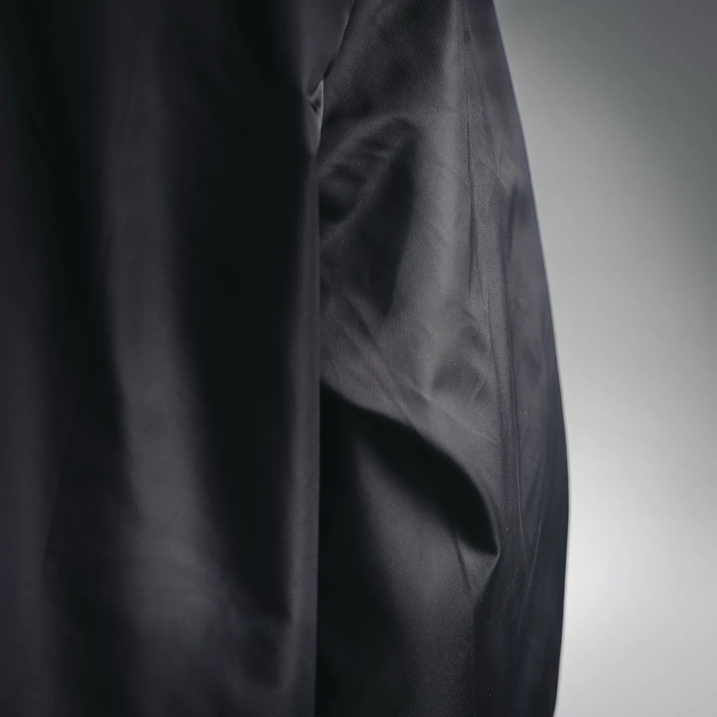 Black jacket side panel close-up with stitched seam and pocket opening