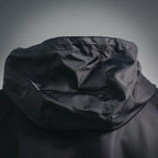 Black hood close-up with draped fabric and stitched seam lines