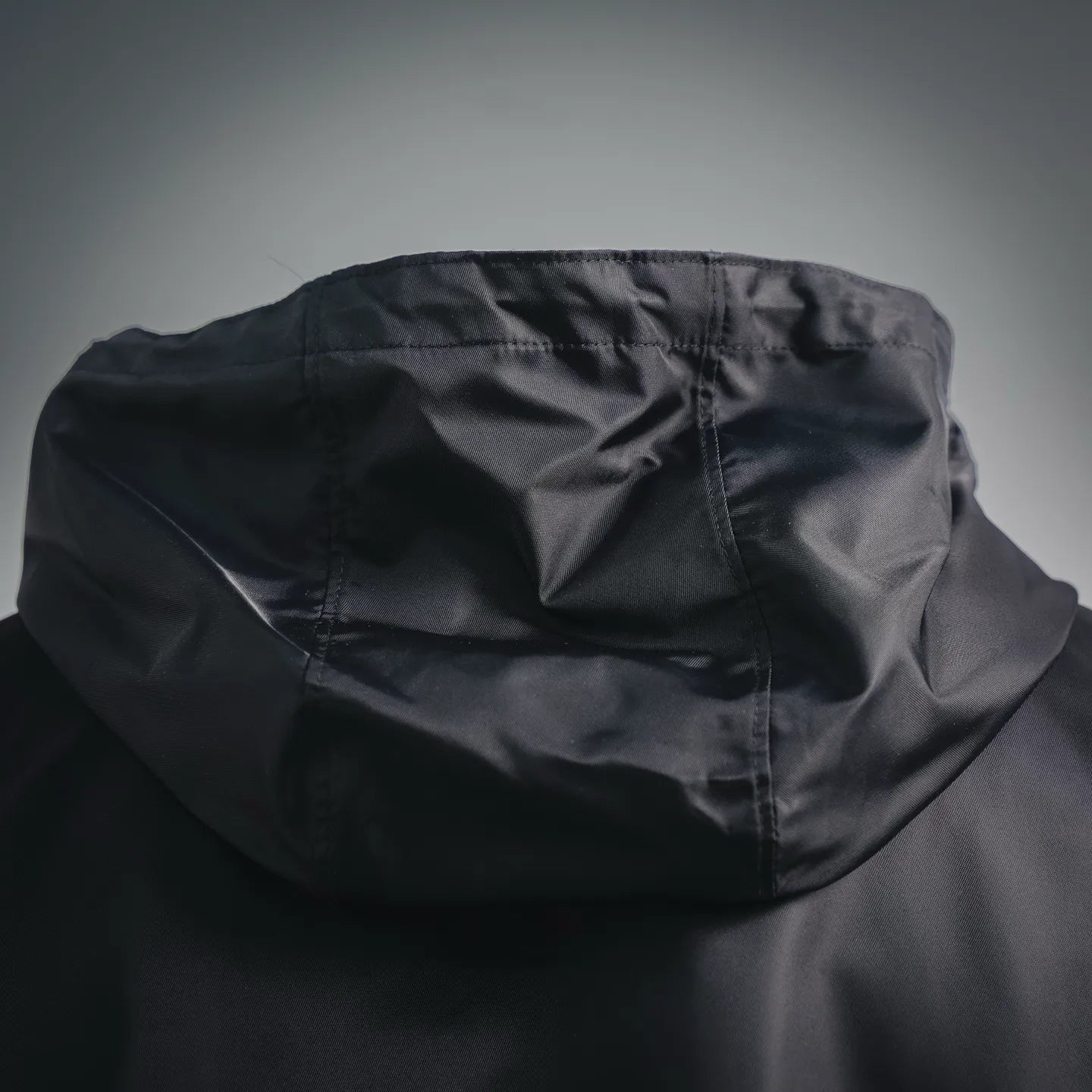 Black hood close-up with draped fabric and stitched seam lines