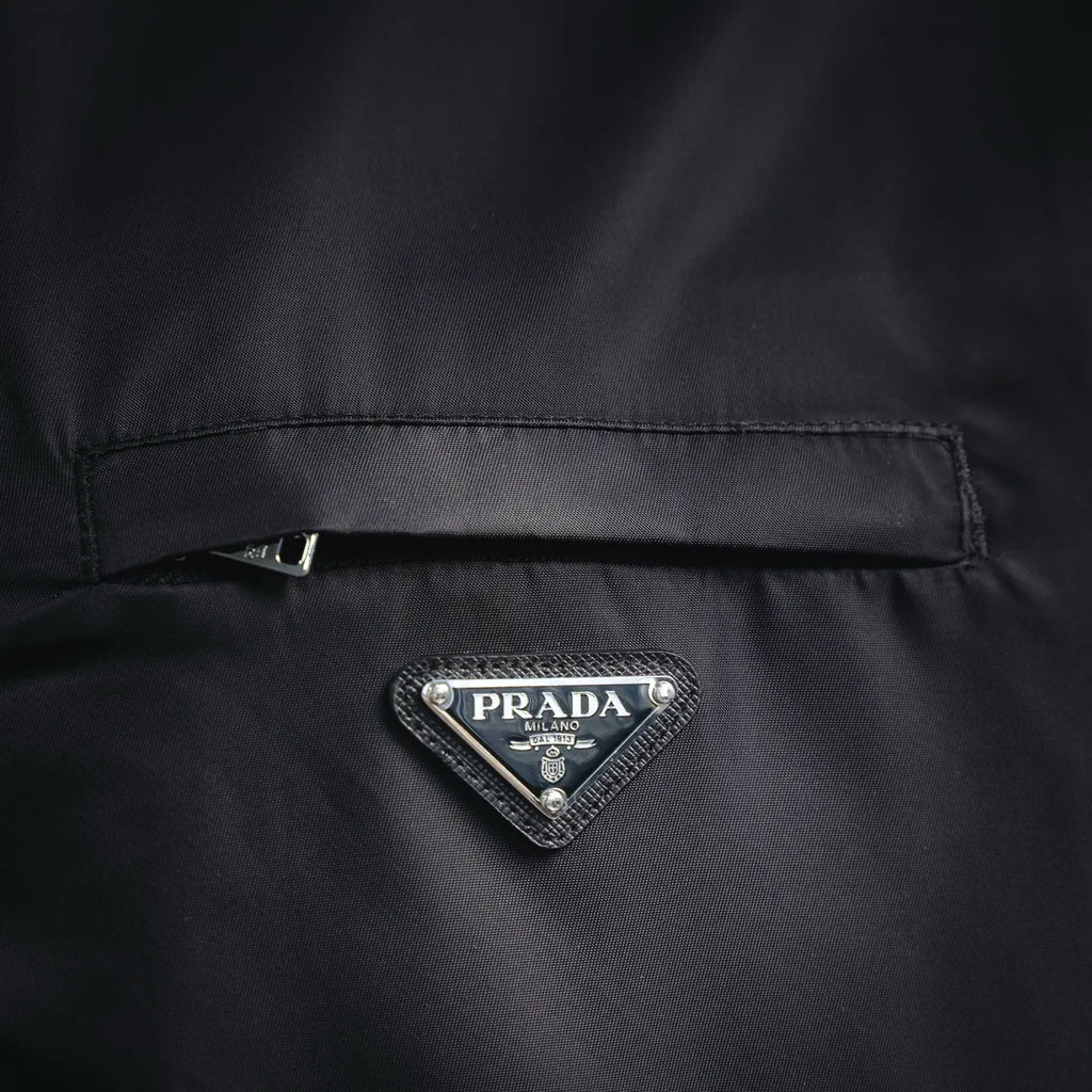 Black jacket chest close-up with PRADA logo triangle and buttoned detail