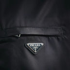 Black jacket chest close-up with PRADA logo triangle and buttoned detail