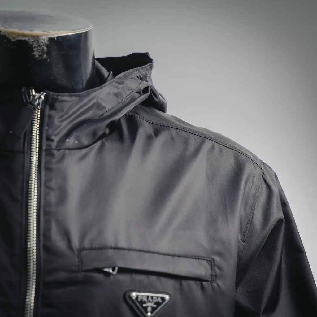 Black jacket shoulder and front close-up with zipper and small logo plaque