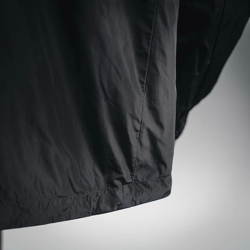 Black nylon jacket hem with elasticized trim and seam detail