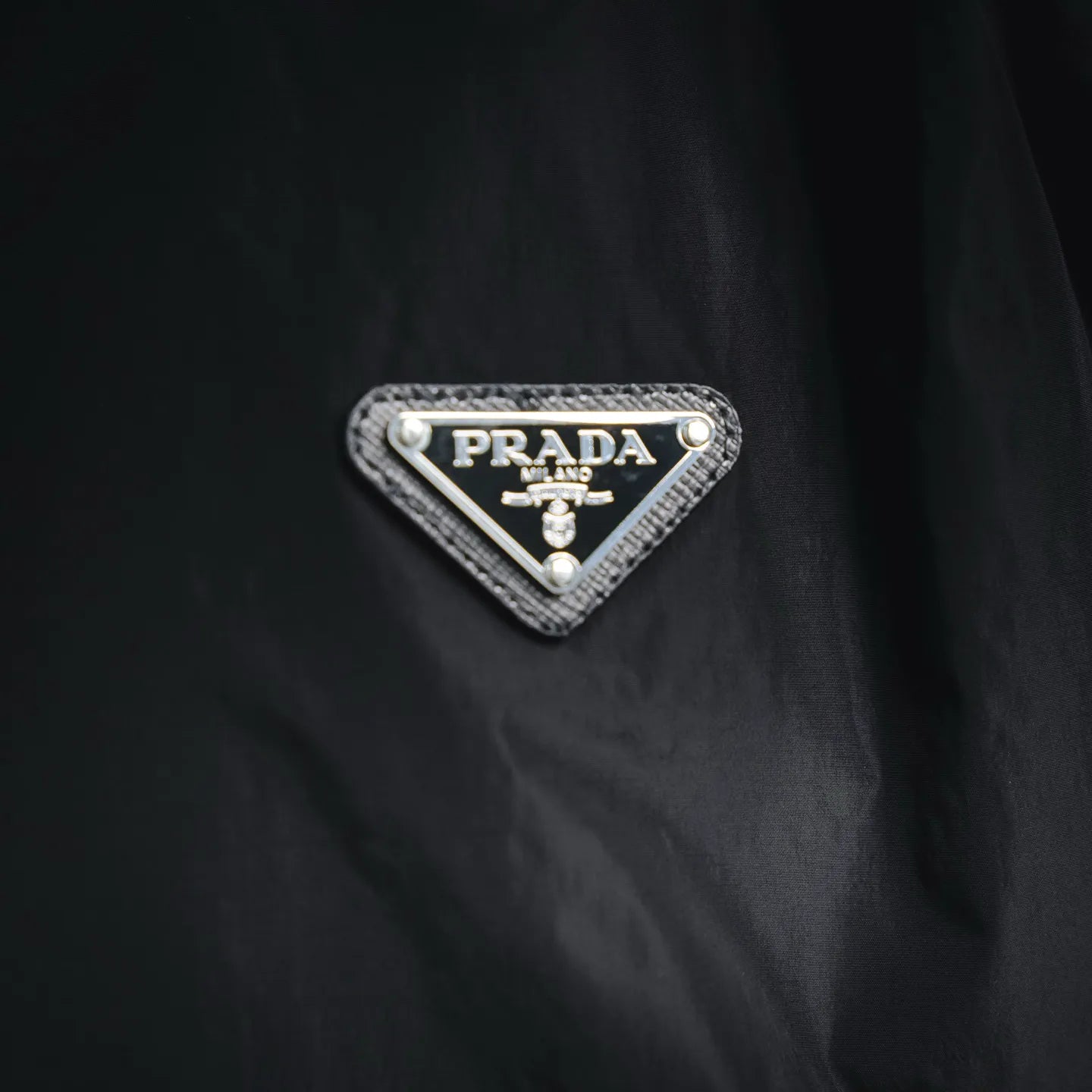 Prada triangular logo patch on black nylon jacket