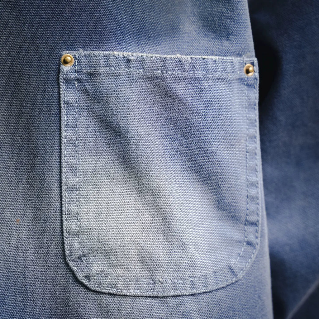 Light blue denim jacket front patch pocket with brass-style button tabs