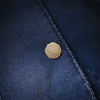 Round brass-style snap button on light blue denim jacket
