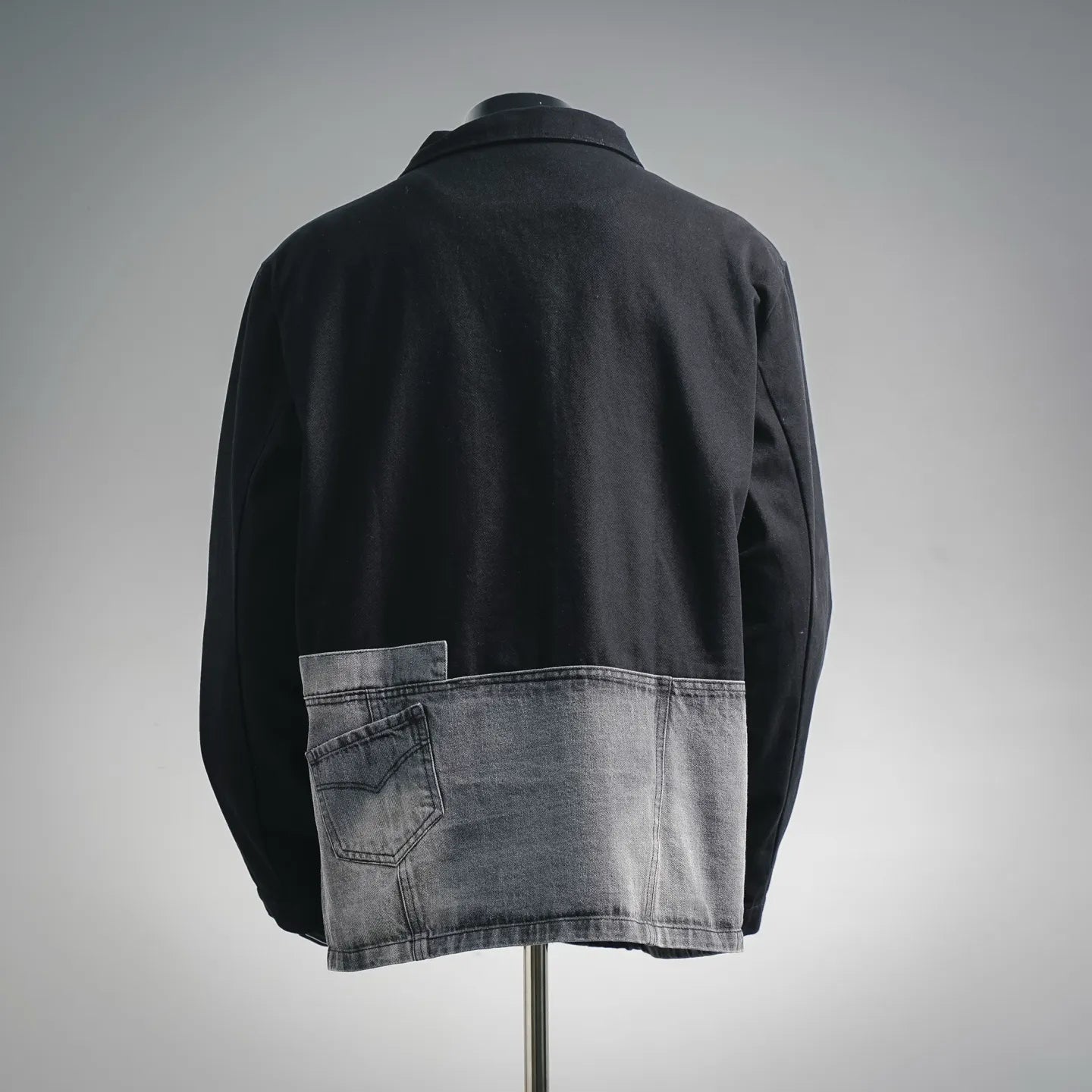 Black zip jacket with gray denim hem panel, back view on mannequin