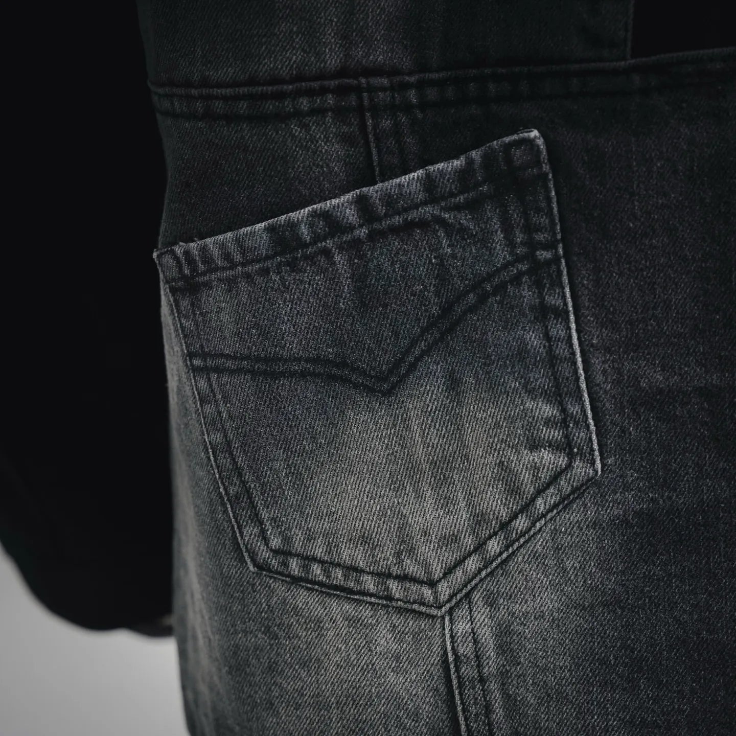 Denim front pocket with stitched panel detail on black jacket
