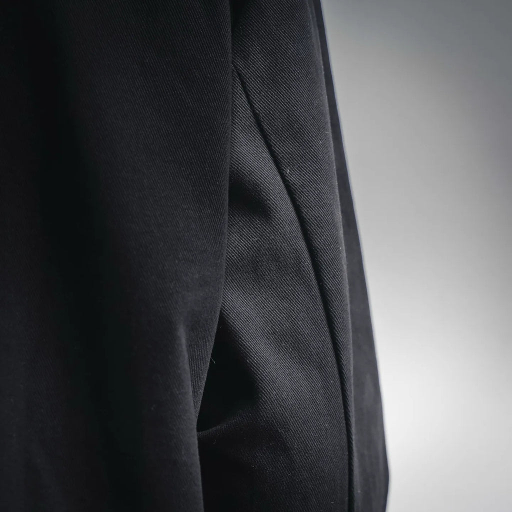 Black jacket sleeve with subtle woven texture, side seam