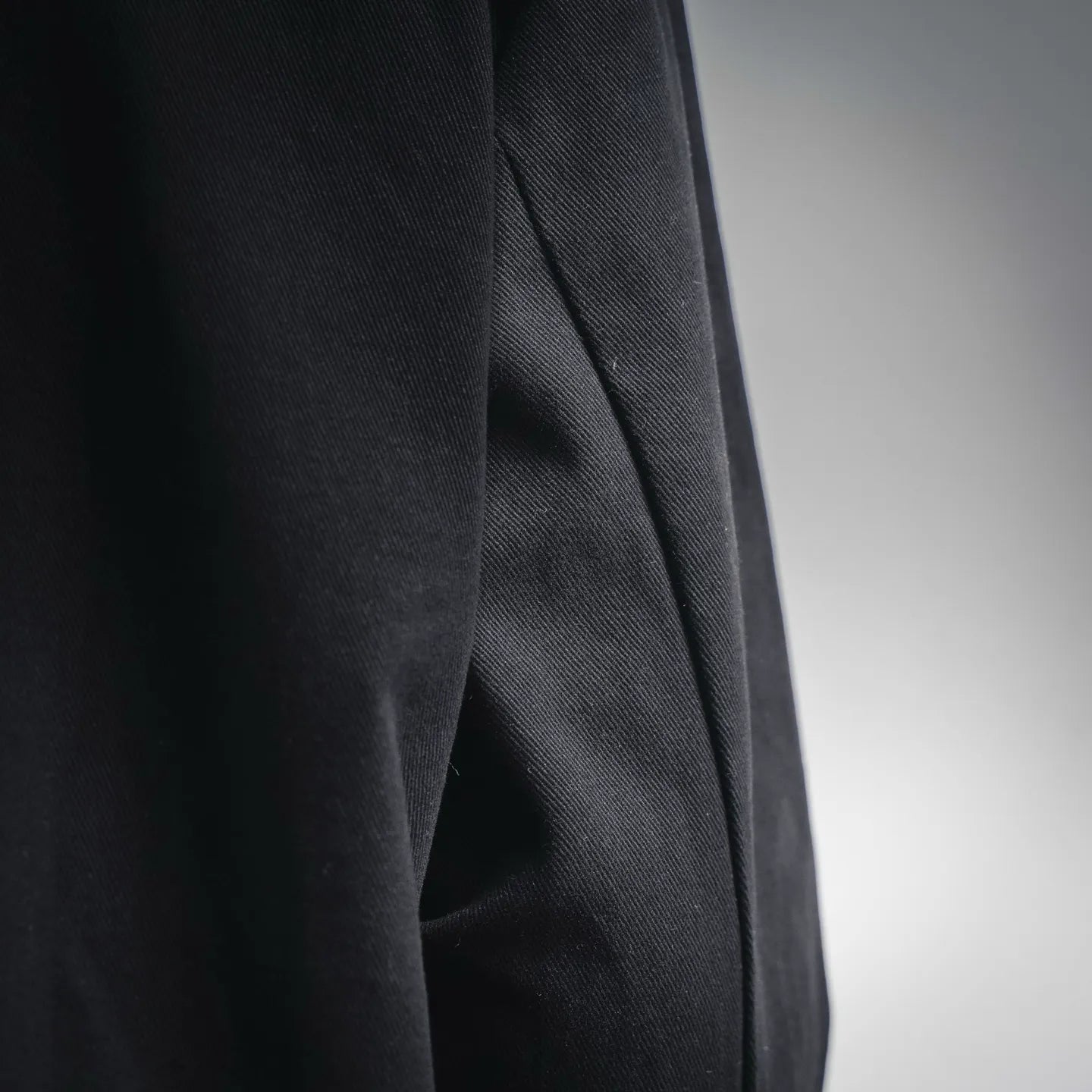 Black jacket sleeve with subtle woven texture, side seam