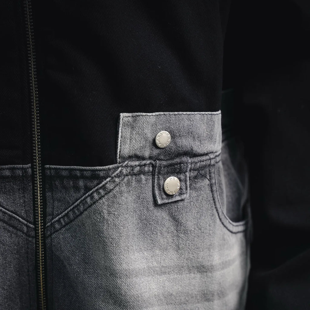 Denim pocket with two silver snap buttons on black jacket