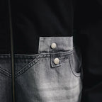 Denim pocket with two silver snap buttons on black jacket