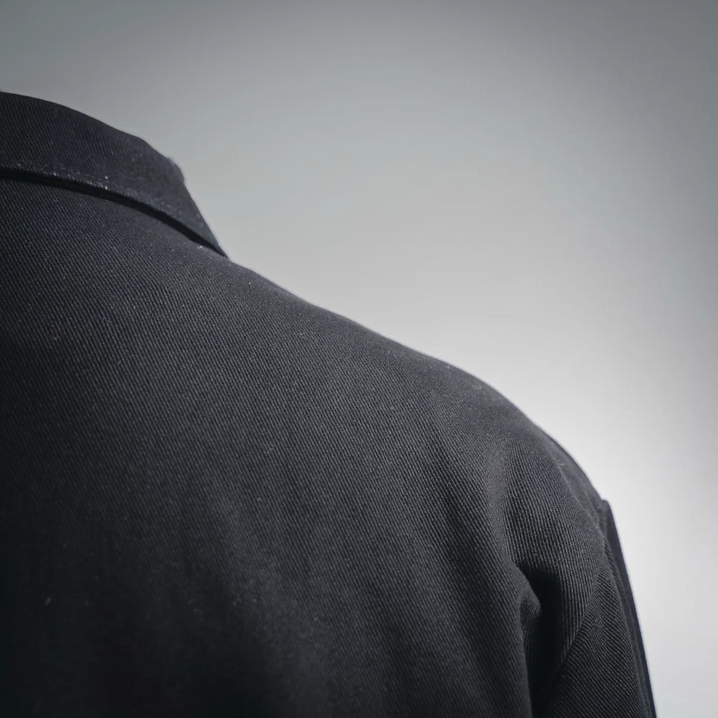 Black jacket shoulder and upper sleeve seam, textured fabric