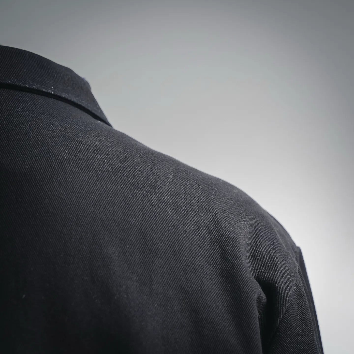 Black jacket shoulder and upper sleeve seam, textured fabric