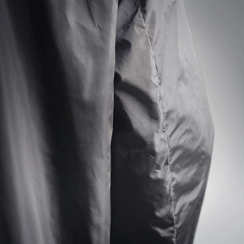 Close-up of dark gray jacket fabric with seam and slight wrinkle texture