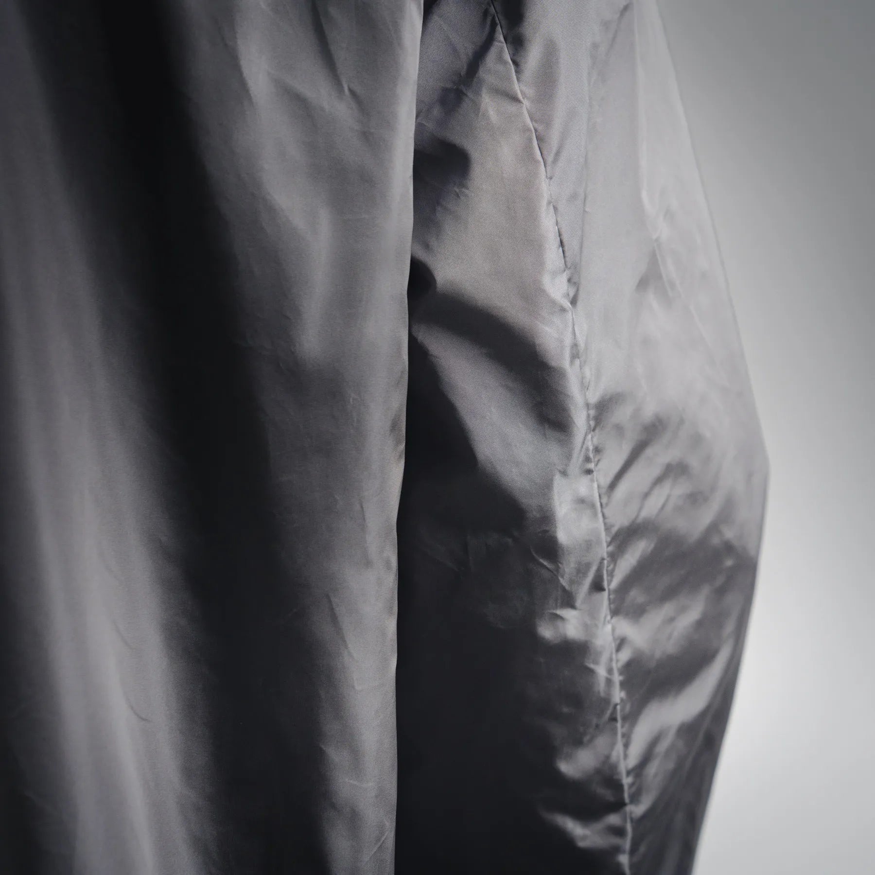 Close-up of dark gray jacket fabric with seam and slight wrinkle texture