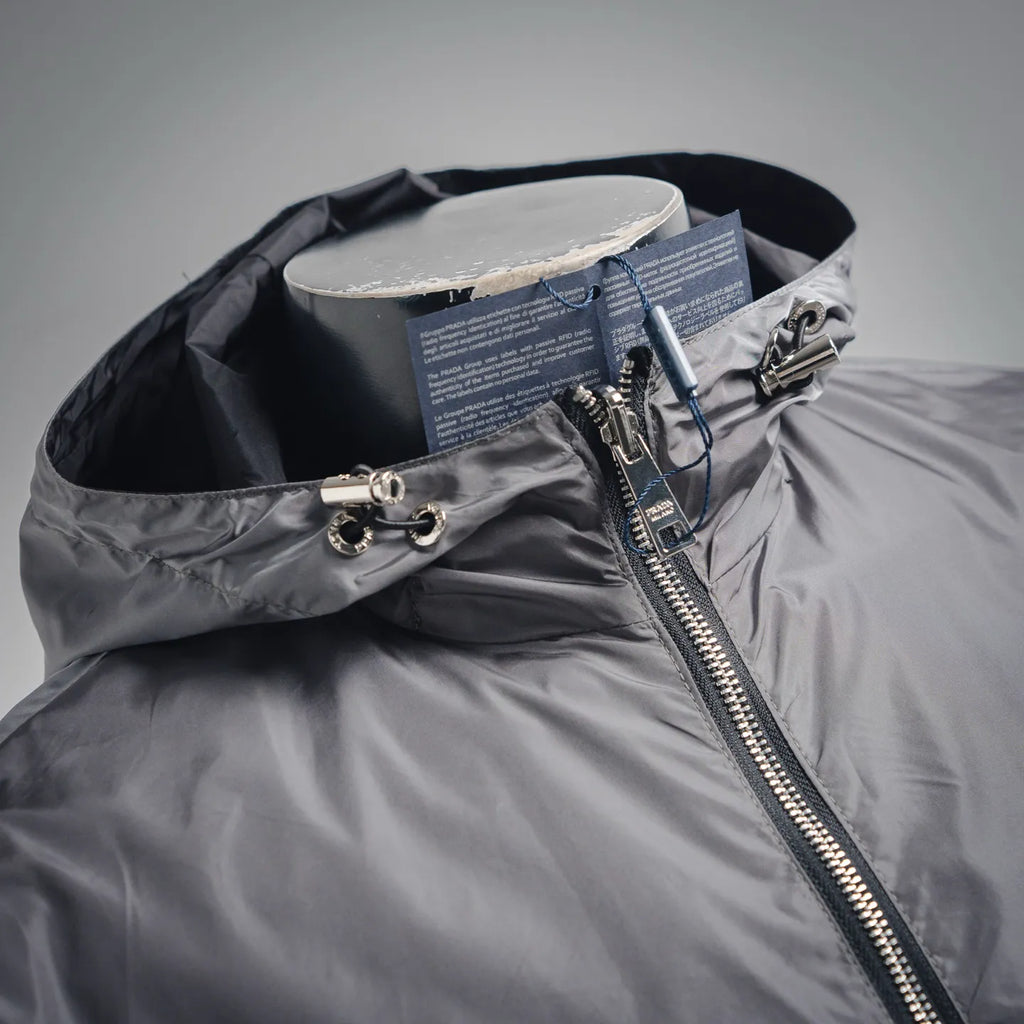 Hood detail of dark gray jacket with front zipper and metal pull ring hardware