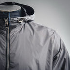 Front upper view of dark gray hooded jacket with zipper and metal hardware at hood