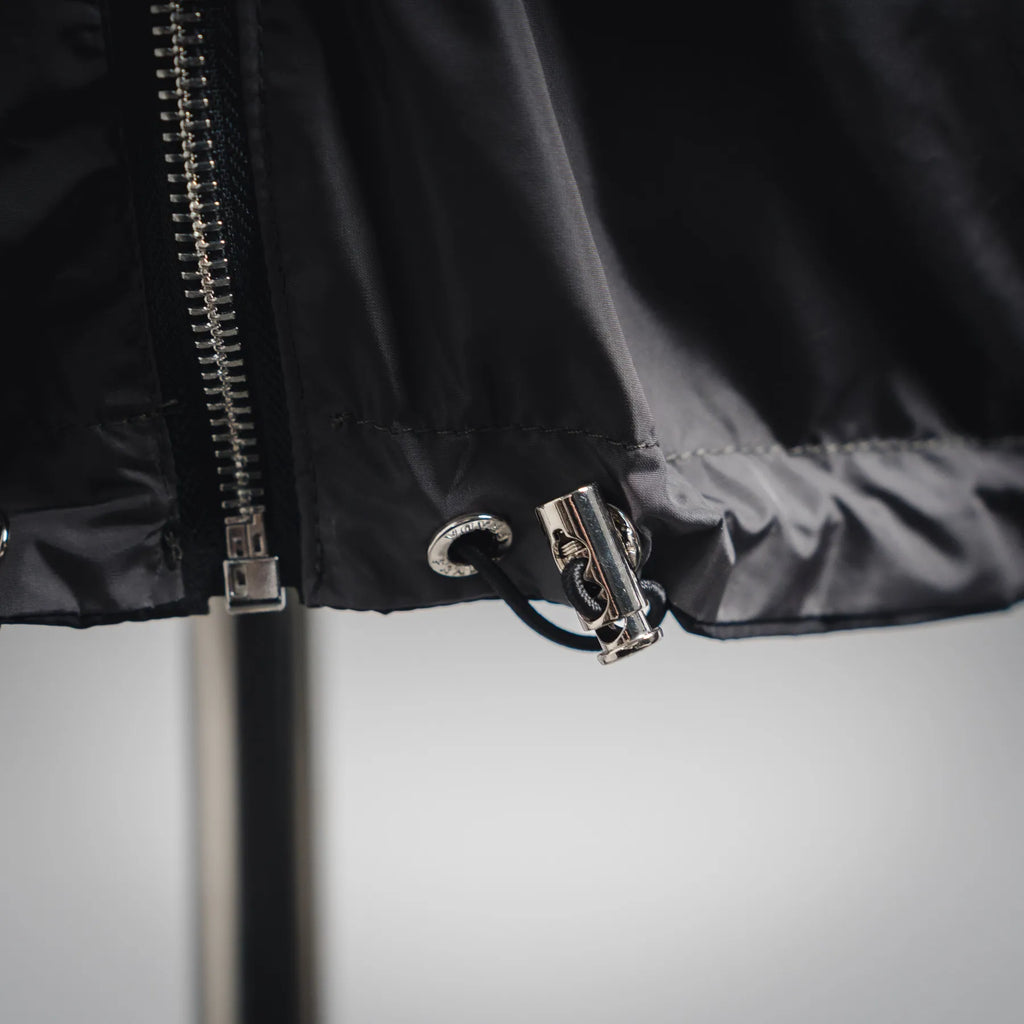 Jacket front hem and zipper pull in dark gray with drawstring toggle detail