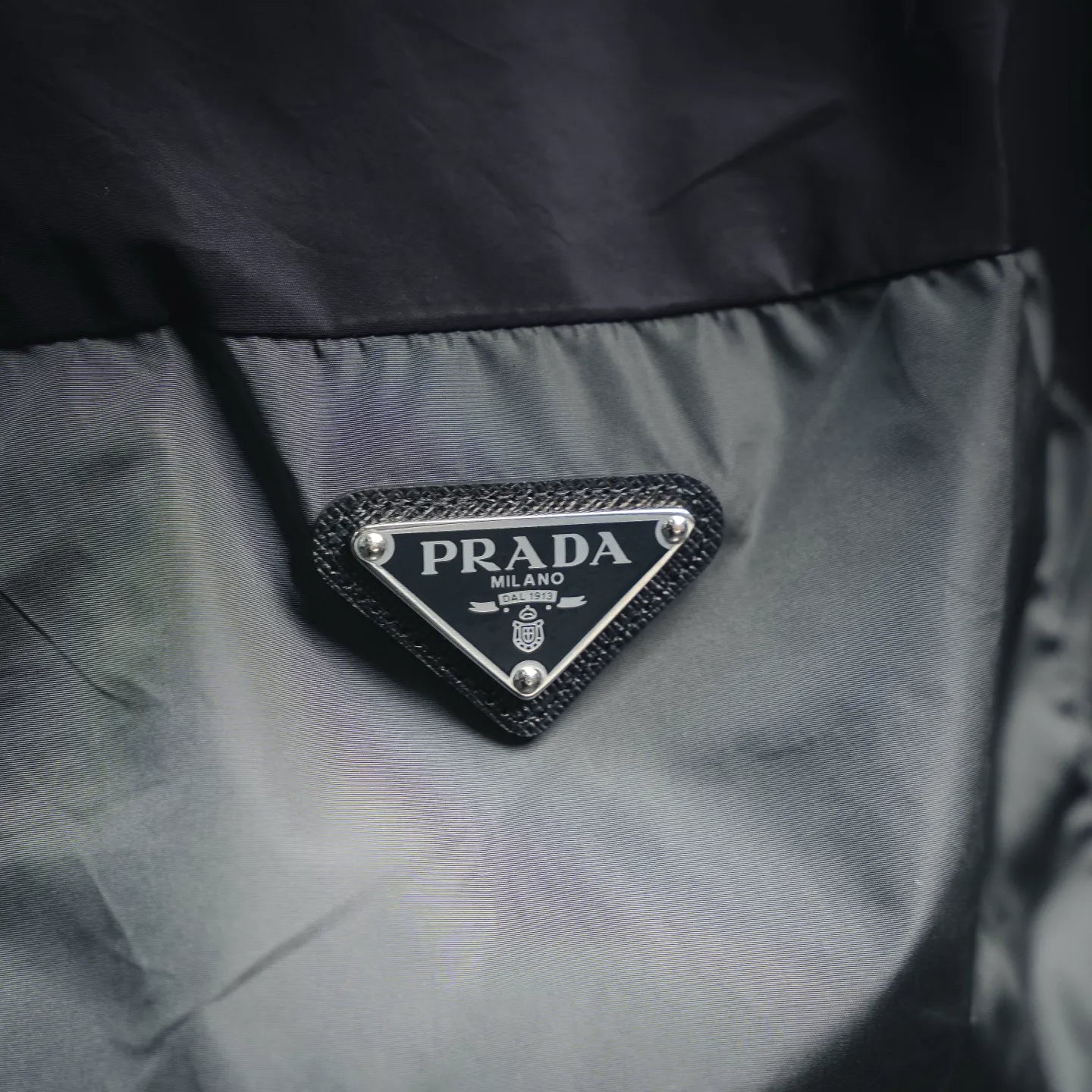Prada triangle logo patch on black jacket chest