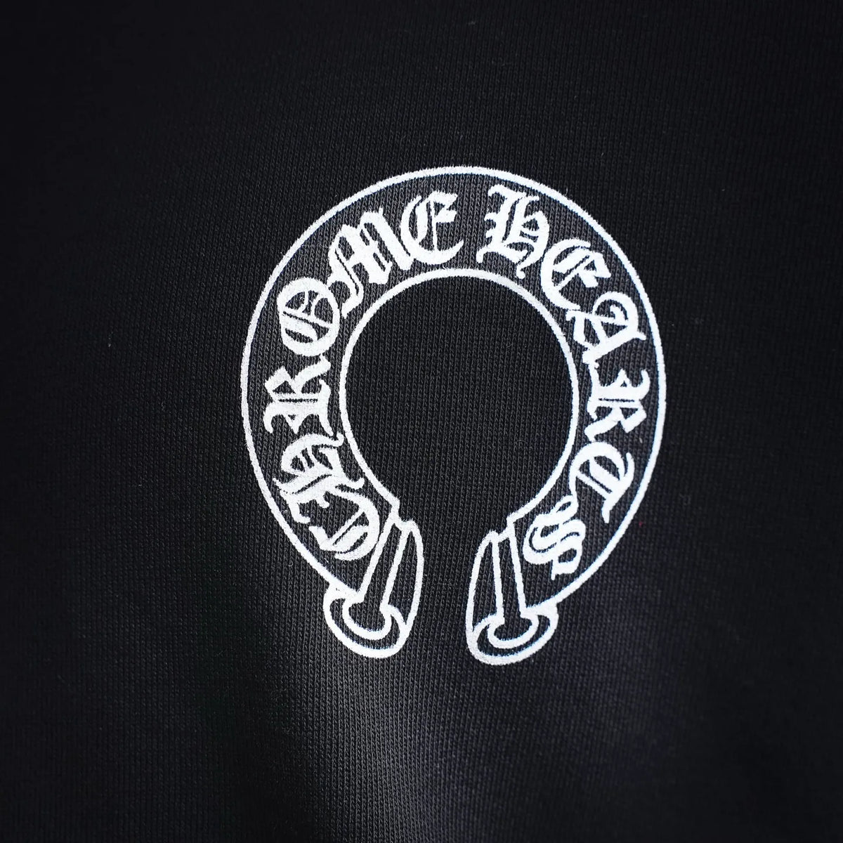 Black sweatshirt sleeve logo with circular white graphic detail