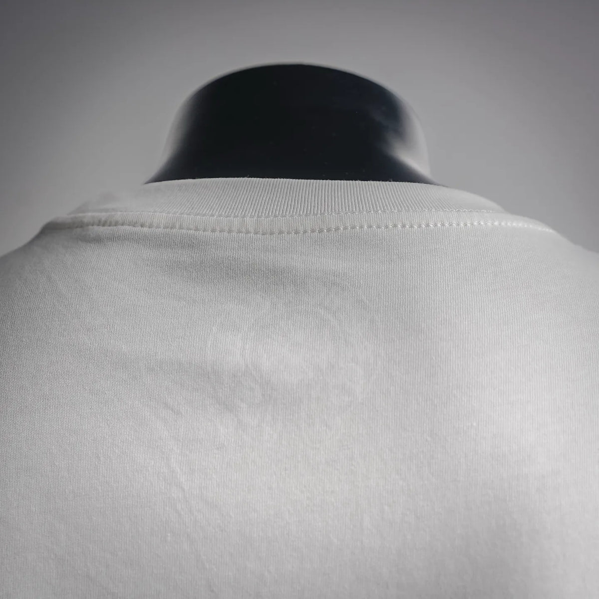 White long-sleeve T-shirt neckline and shoulder seam close-up