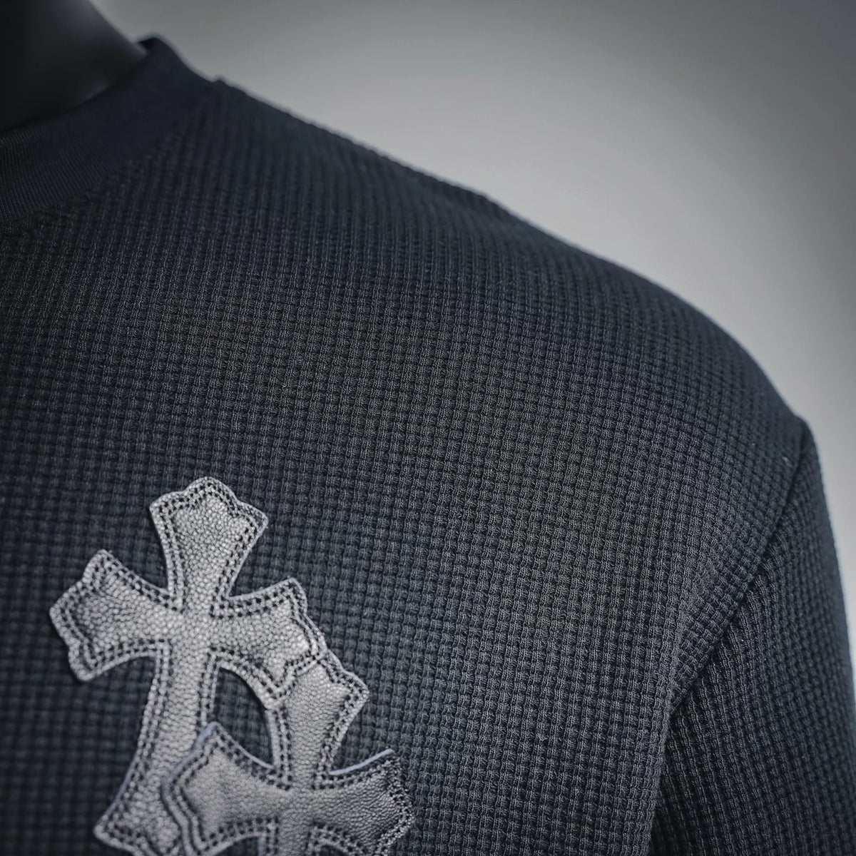 Dark henley with embroidered silver cross patch on the left shoulder