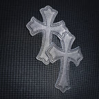 Embroidered silver cross motif on the chest of a dark long-sleeve henley